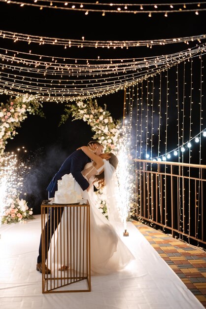 Los recién casados se ríen felizmente y prueban el pastel de bodas