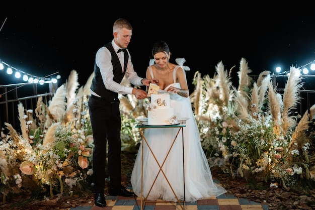 Los recién casados se ríen felizmente y prueban el pastel de bodas