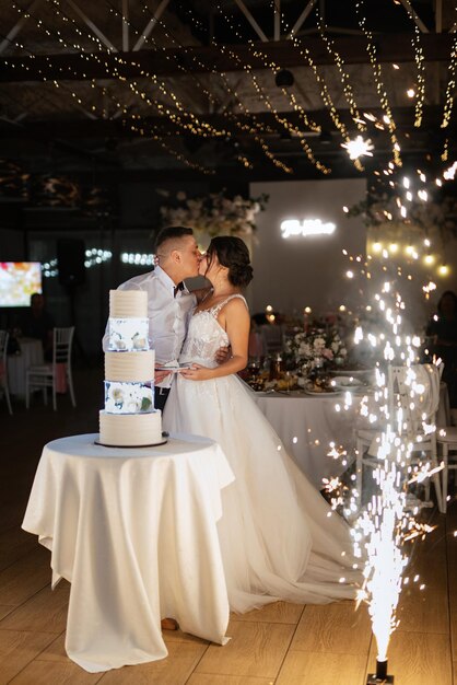 Los recién casados se ríen felizmente y prueban el pastel de bodas