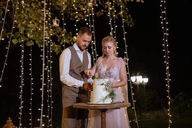 Los recién casados se ríen felizmente y prueban el pastel de bodas