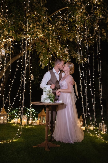 Los recién casados se ríen felizmente y prueban el pastel de bodas