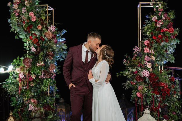 Recién casados por la tarde en el arco de la boda