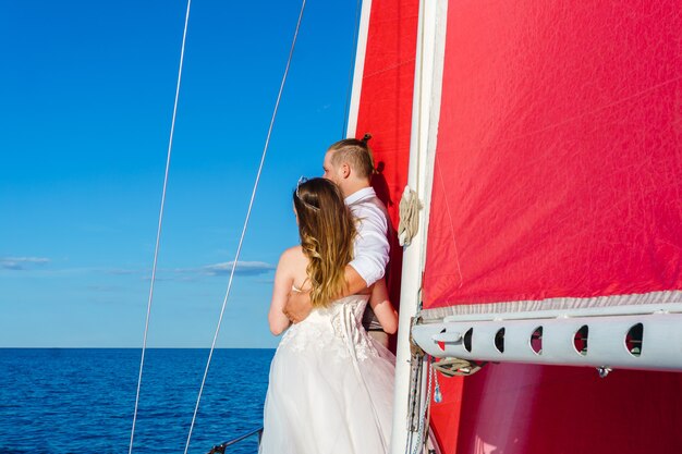 Recién casados en un viaje de bodas al mar en un yate de vela