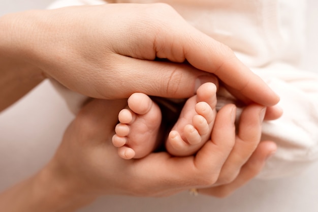 Foto un recién nacido se aferra al dedo de papá y mamá. cerca de las manos de los padres y del bebé. un niño confía y la abraza fuerte. foto de alta calidad