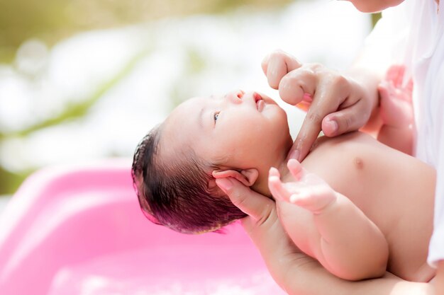 Recién nacido asiático tomando un baño en la cuenca de ping por nueva madre