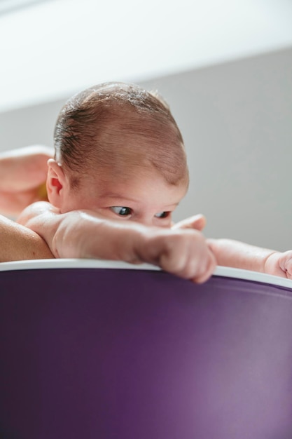 Recién nacido en la bañera sostenido por su madre