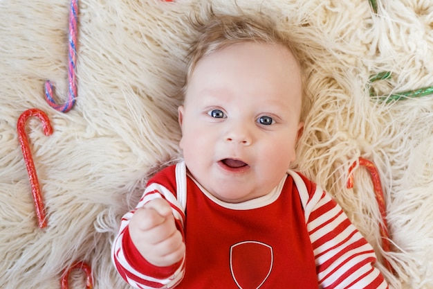 Recién nacido hasta cinco meses en pijama rojo se encuentra entre confers multicolores