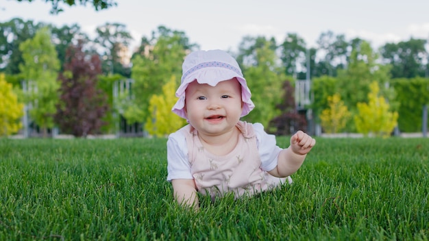 Recién nacido niña lactante tumbado en el césped de un parque en un día de verano