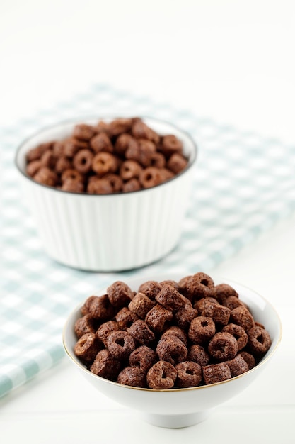 Recipiente con anillos de maíz de chocolate sobre fondo blanco.