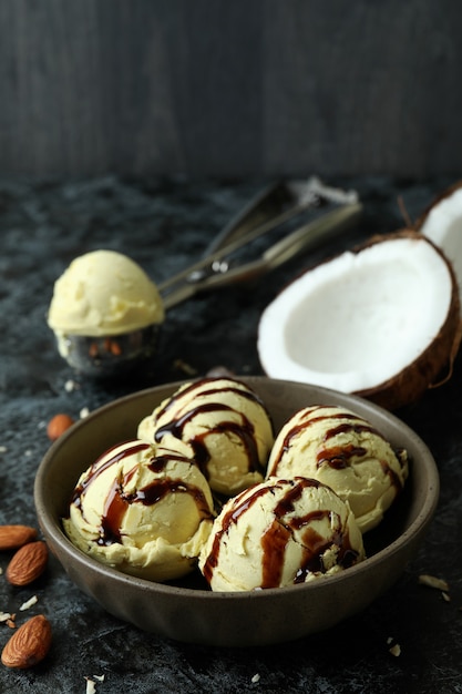 Recipiente con bolas de helado e ingredientes en la mesa ahumada negra