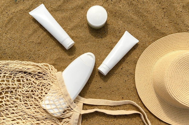 recipiente branco para creme na areia saco de fio branco e chapéu de sol
