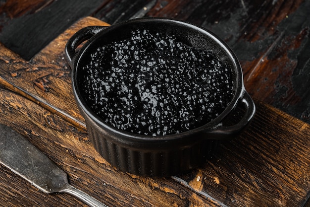 Foto recipiente de caviar negro sobre la vieja mesa de madera oscura.