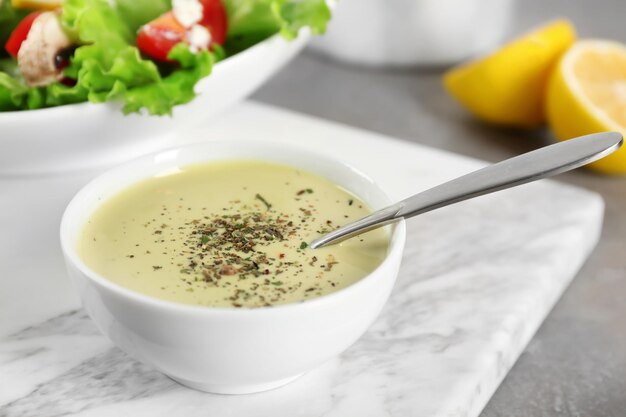 Recipiente de cerámica con aderezo ranch para ensaladas en la mesa