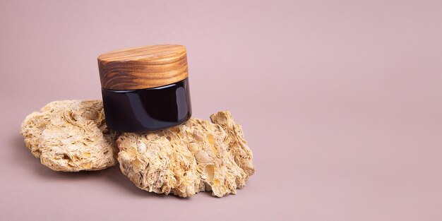 Recipiente de creme ecológico com tampa de madeira nas pedras naturais Bom como maquete de cosméticos