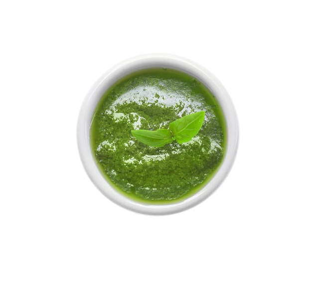 Recipiente con deliciosa salsa de pesto de albahaca sobre fondo blanco.