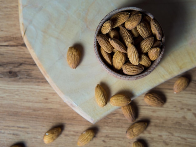 Recipiente con deliciosas almendras en una mesa de madera