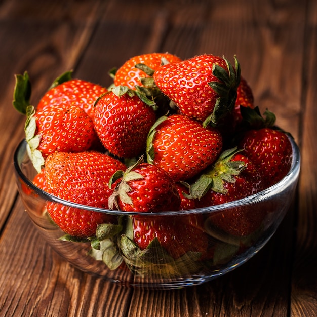 Recipiente con fresas frescas sobre mesa de madera