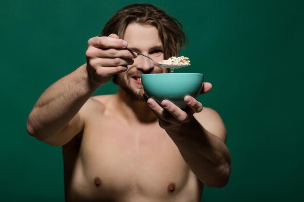 Recipiente con gachas de avena al hombre feliz musculoso desnudo