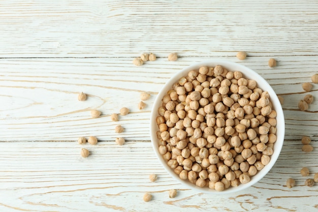 Recipiente con garbanzos sobre mesa de madera blanca