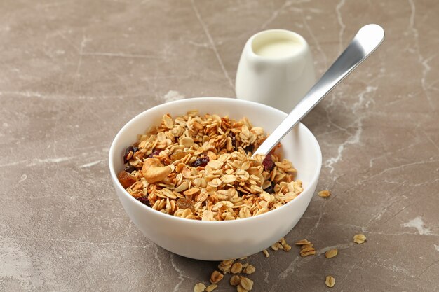 Foto recipiente con granola y leche sobre fondo gris