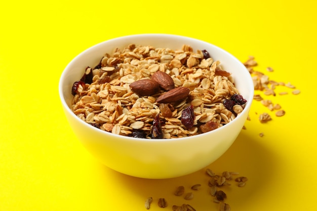 Recipiente con granola con nueces y pasas sobre fondo amarillo