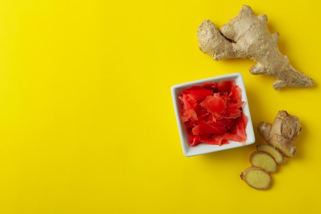 Recipiente con jengibre encurtido rojo y jengibre sobre amarillo