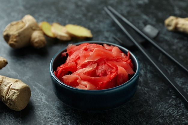 Recipiente con jengibre en escabeche rojo y palillos en negro ahumado