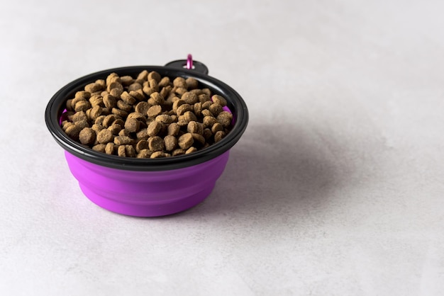 Recipiente para mascotas de silicona plegable lila con comida sobre fondo gris Espacio de copia