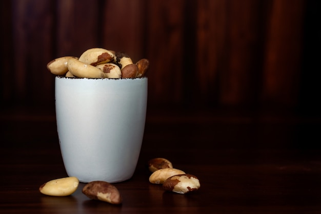 Recipiente con nueces brasileñas sobre mesa de madera. Nuez de Brasil o Bertholletia