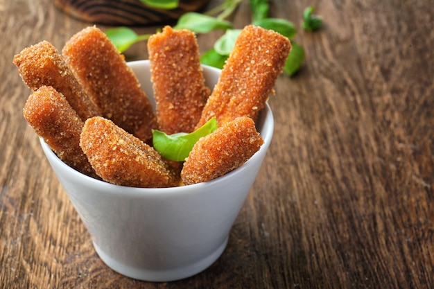 Recipiente con palitos de queso en la mesa