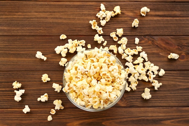 Recipiente con palomitas de maíz frescas sobre fondo de madera