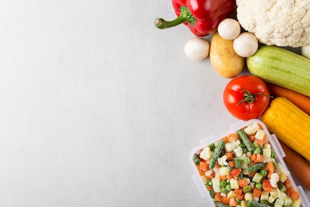 Recipiente de plástico rectangular con una mezcla de verduras congeladas vista superior con espacio de copia y alimentos frescos