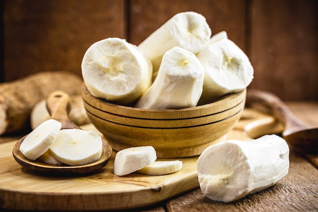 Recipiente con raíces de yuca sobre mesa de madera rústica