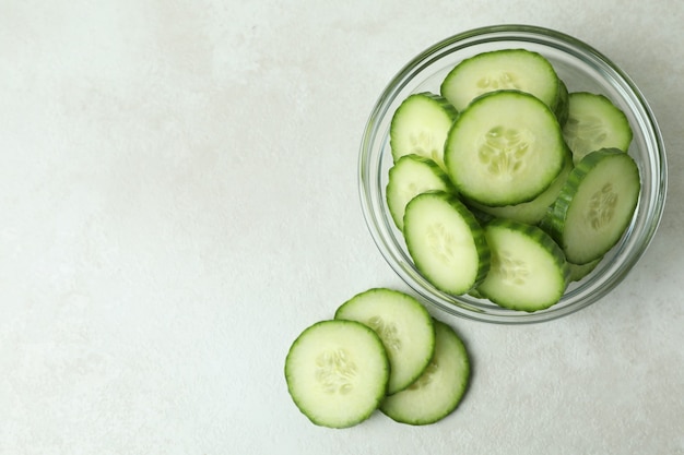 Recipiente con rodajas de pepino sobre fondo blanco aislado con textura