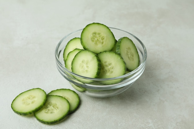 Recipiente con rodajas de pepino sobre fondo blanco aislado con textura