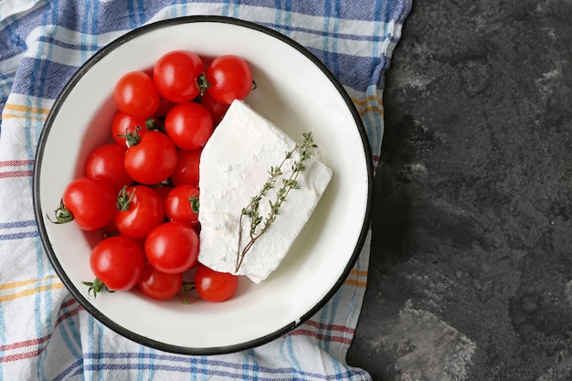 Recipiente con sabroso queso feta y tomates en gris