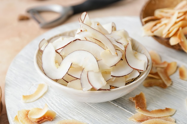 Recipiente con sabrosos chips de coco en la mesa