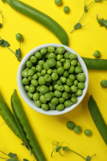 Recipiente con semillas de guisantes frescas sobre fondo amarillo