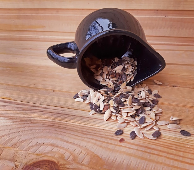 Recipiente con semillas volcado sobre fondo de madera