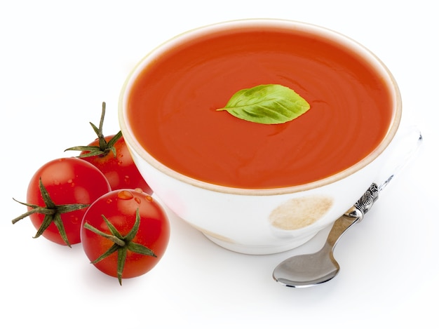 Recipiente con sopa de tomate tomate gazpacho hoja de albahaca y cuchara