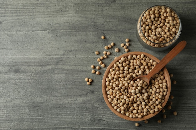 Recipiente, tarro y cuchara con garbanzos en mesa gris