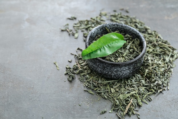 Recipiente con té verde seco sobre una superficie oscura