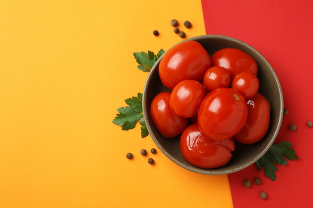 Recipiente con tomates en escabeche y especias sobre fondo de dos tonos