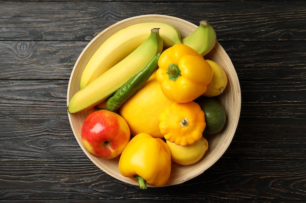 Recipiente con verduras y frutas sobre fondo de madera