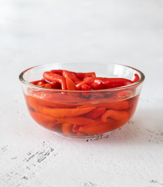 Recipiente de vidrio de chiles en escabeche en el cuadro blanco