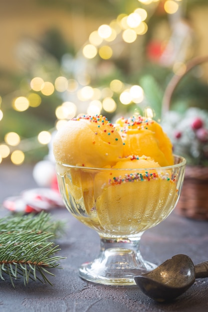 Recipiente de vidrio con delicioso helado de cítricos sobre fondo de Navidad