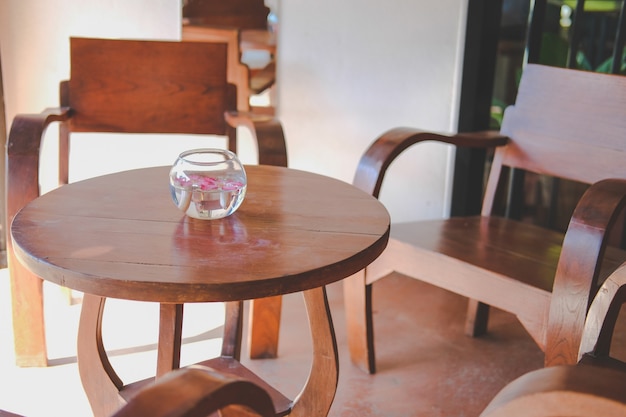 Recipiente de vidrio con flor flotando en el agua decorando sobre mesa de madera en la sala de estar en casa