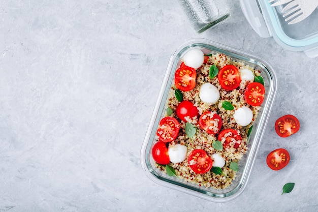 Recipientes de lancheira de preparação de refeição vegetariana com tomates de queijo mussarela de quinoa e manjericão Espaço de cópia de vista superior