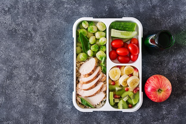 Recipientes de preparação de refeição verde saudável com filé de frango, arroz, couve de bruxelas, legumes e frutas