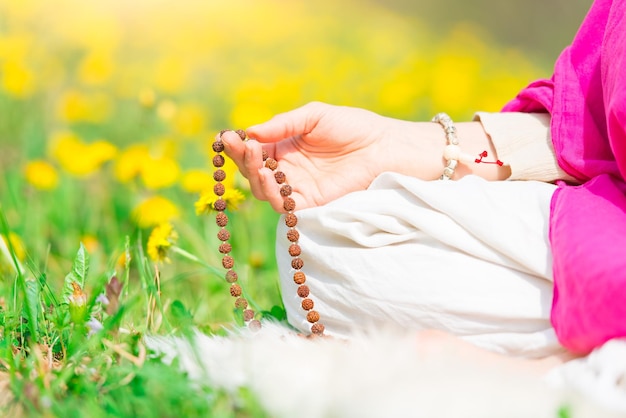 Recitación de mantras sosteniendo el mala durante una práctica de yoga